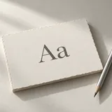 An ivory sheet printed with Aa beside a silver pencil